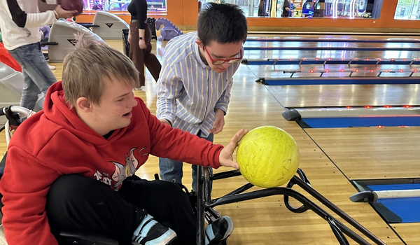 Dos chicos jóvenes con discapacidad jugando a los bolos.