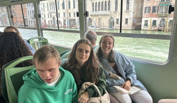 Tres jóvenes, uno de ellos con discapacidad, sentados en unos asientos en un tren haciendo interrail.