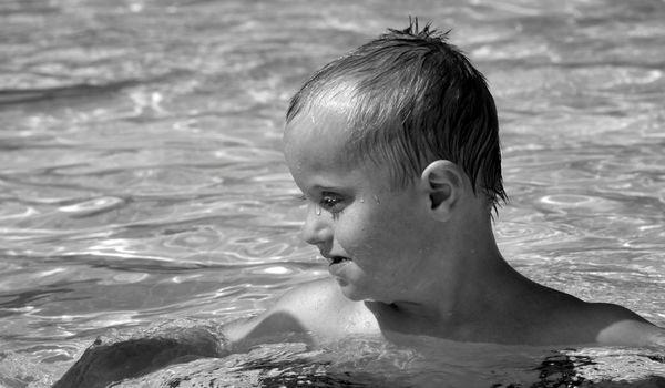 Niño pequeño con discapacidad nadando en una piscina.